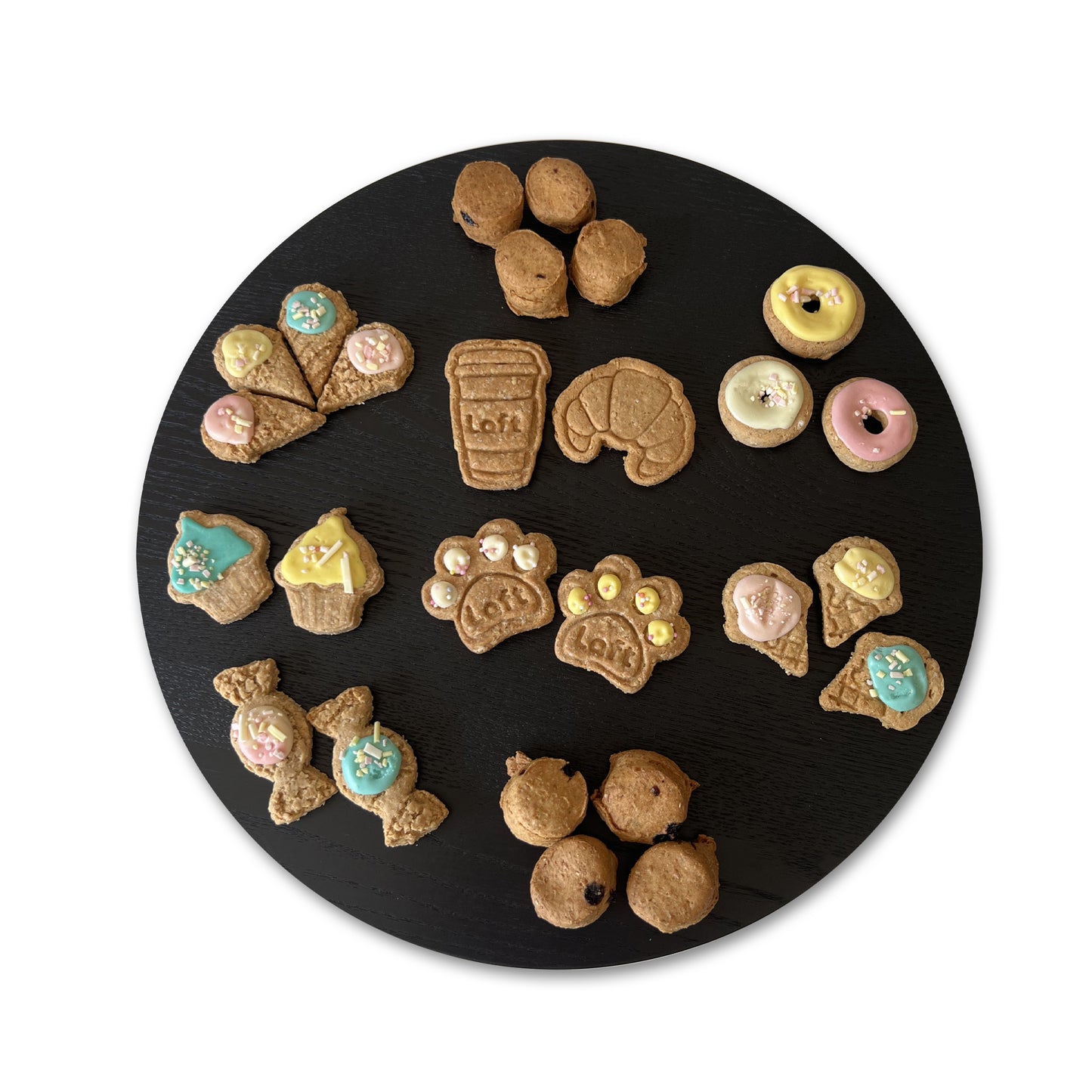 A round black serving platter displays various treats: Laft paw cookie, coffee cup, crepe, croissant, cupcake, donut, ice-cream cone, lolly and scone.