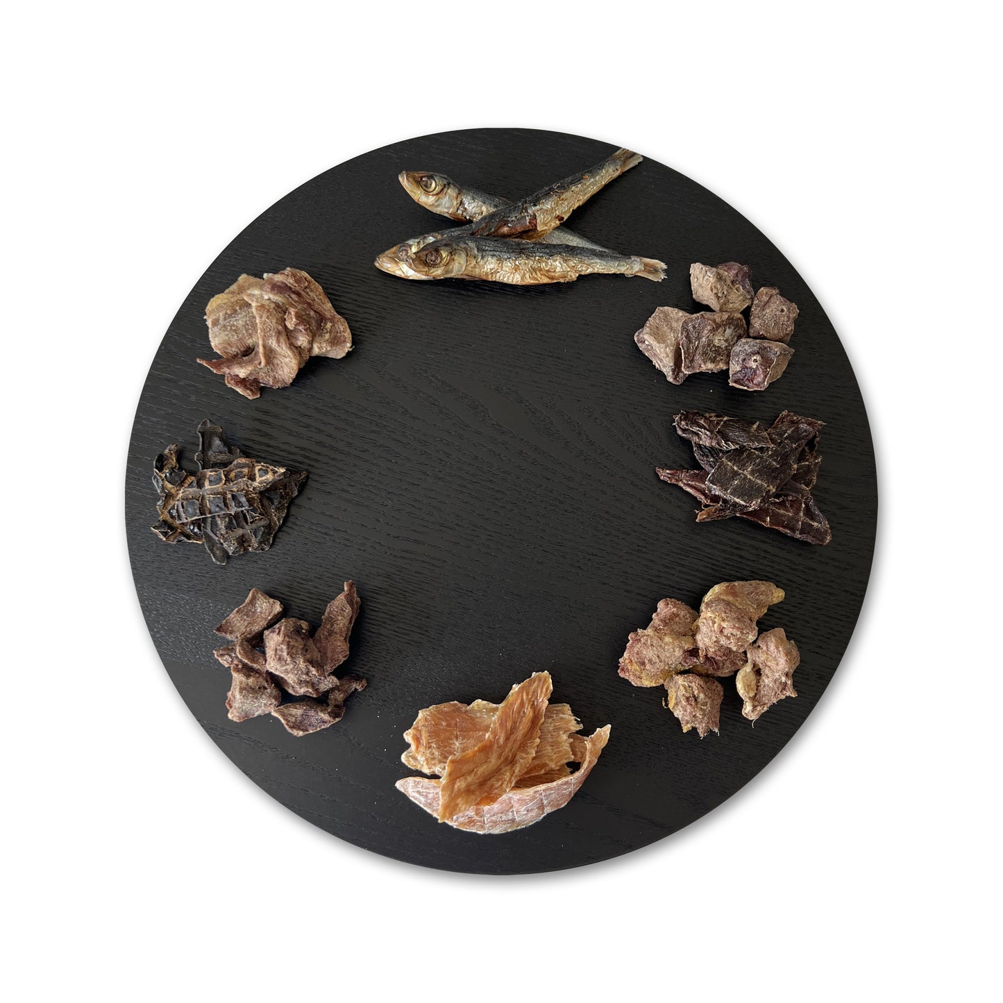 A round black serving platter displays various treats.
Dehydrated: Chicken Jerky, Lamb Liver, Roo Jerky, and Pilchards.
Freeze Dried: Beef Heart, Emu, Turkey, and Wild Boar.