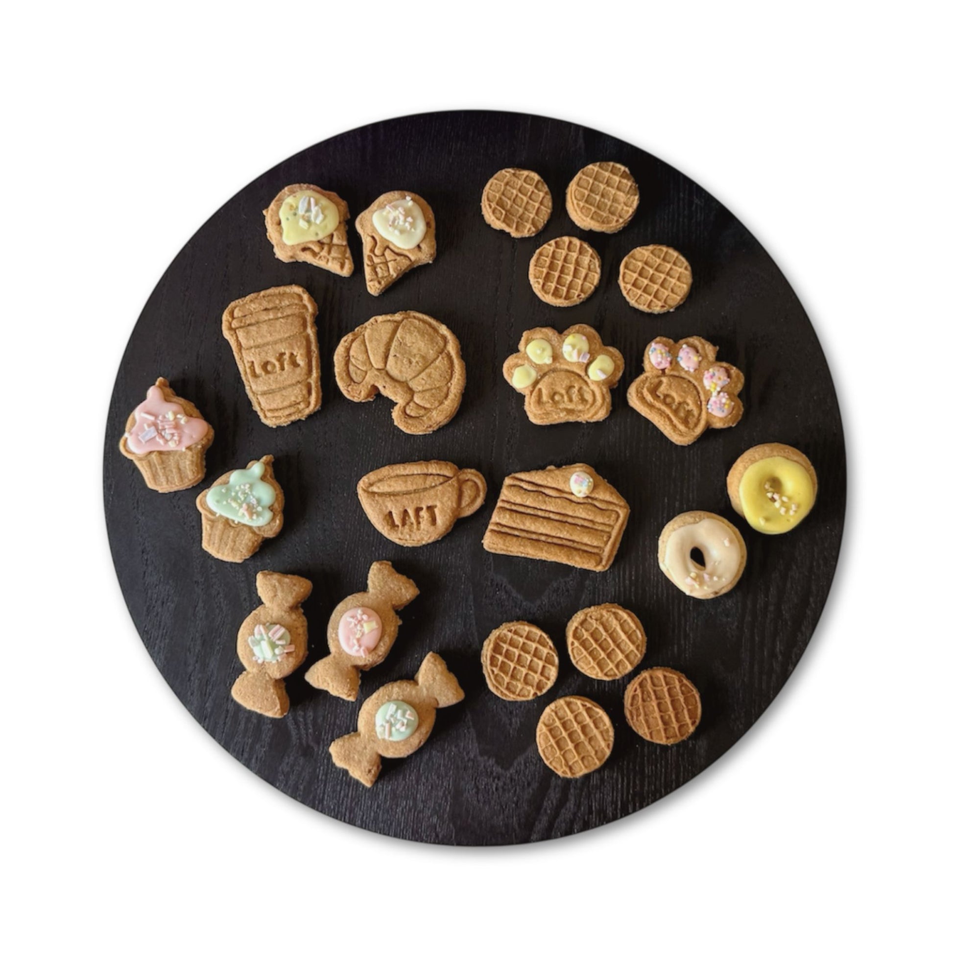 A round black serving platter displays various treats: Laft coffee cup, croissant, paw cookies, cappuccino, cake slice, cupcake, donut, ice-cream cone, lolly and waffle.
