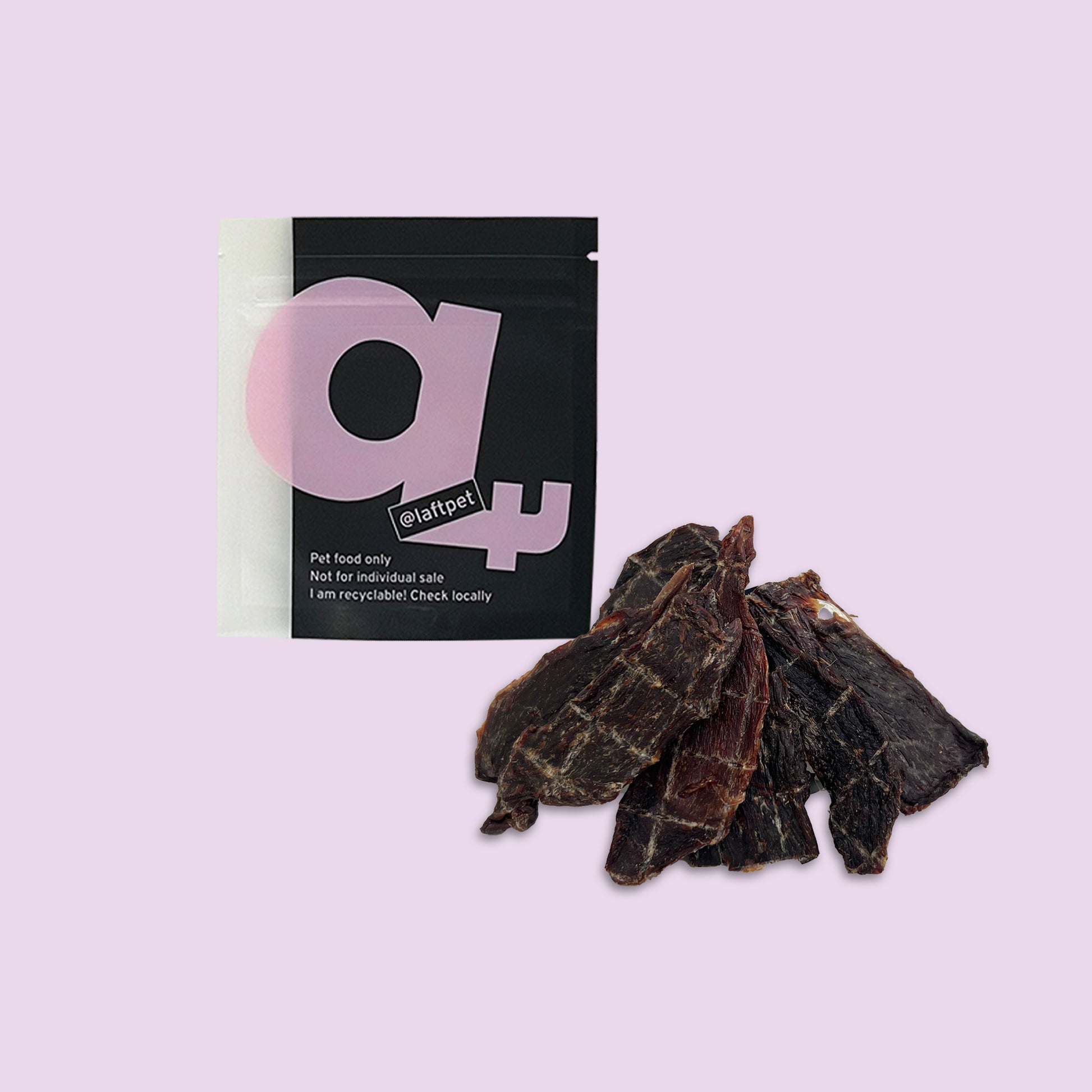 A black Laft Pet natural dog treat pouch placed next to a pile of dehydrated kangaroo jerky dog treats on a light purple background.