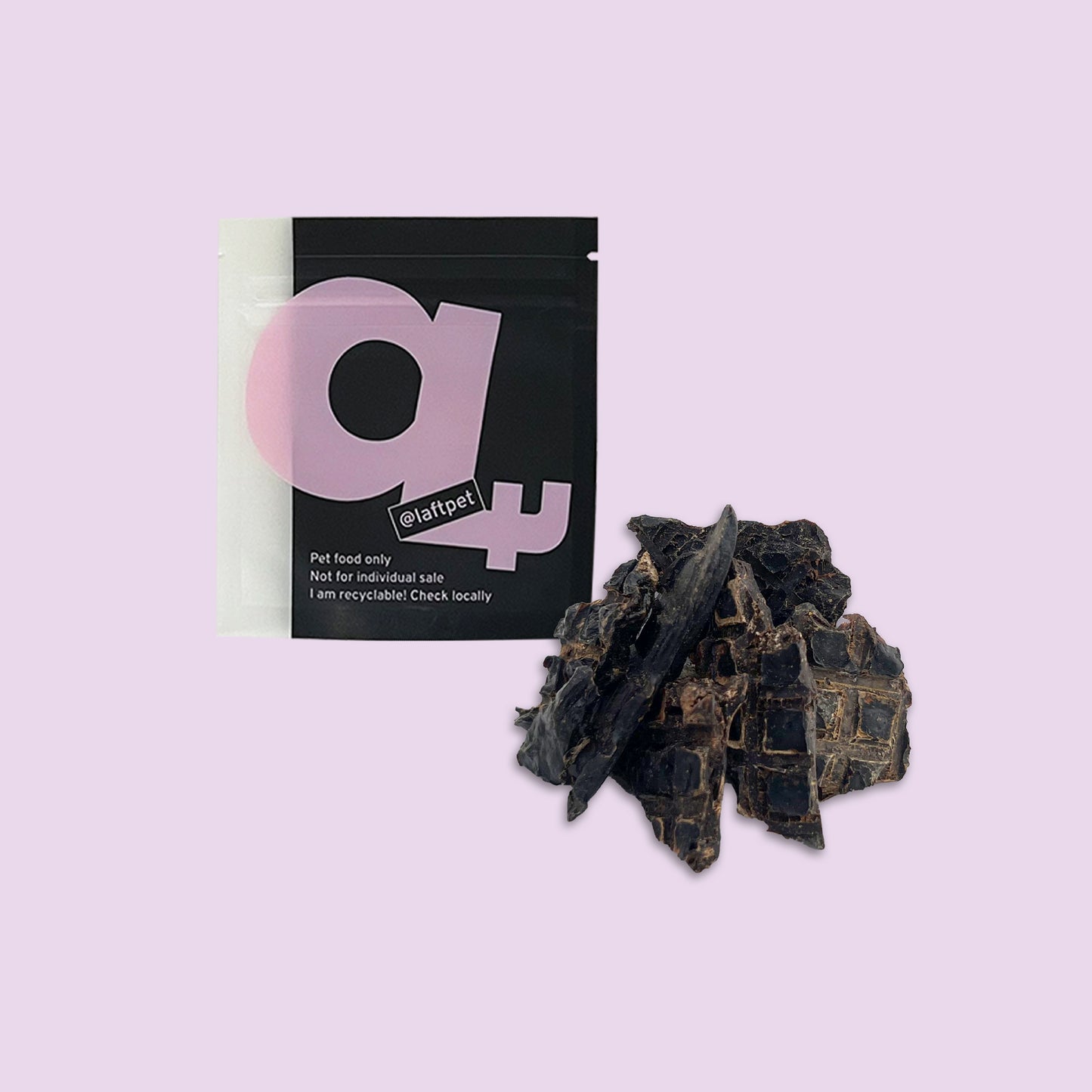 A black Laft Pet natural dog treat pouch placed next to a pile of dehydrated lamb liver dog treats on a light purple background.