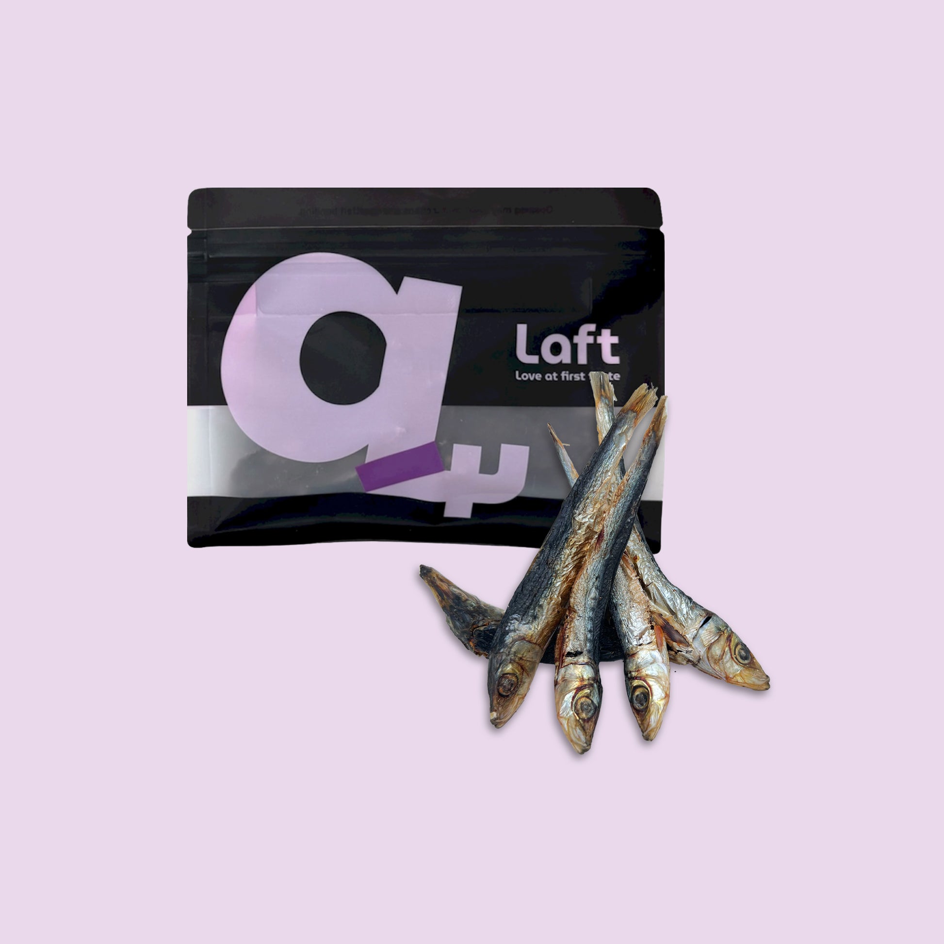 A black Laft Pet natural dog treat pouch placed next to a pile of dehydrated pilchards dog treats on a light purple background.