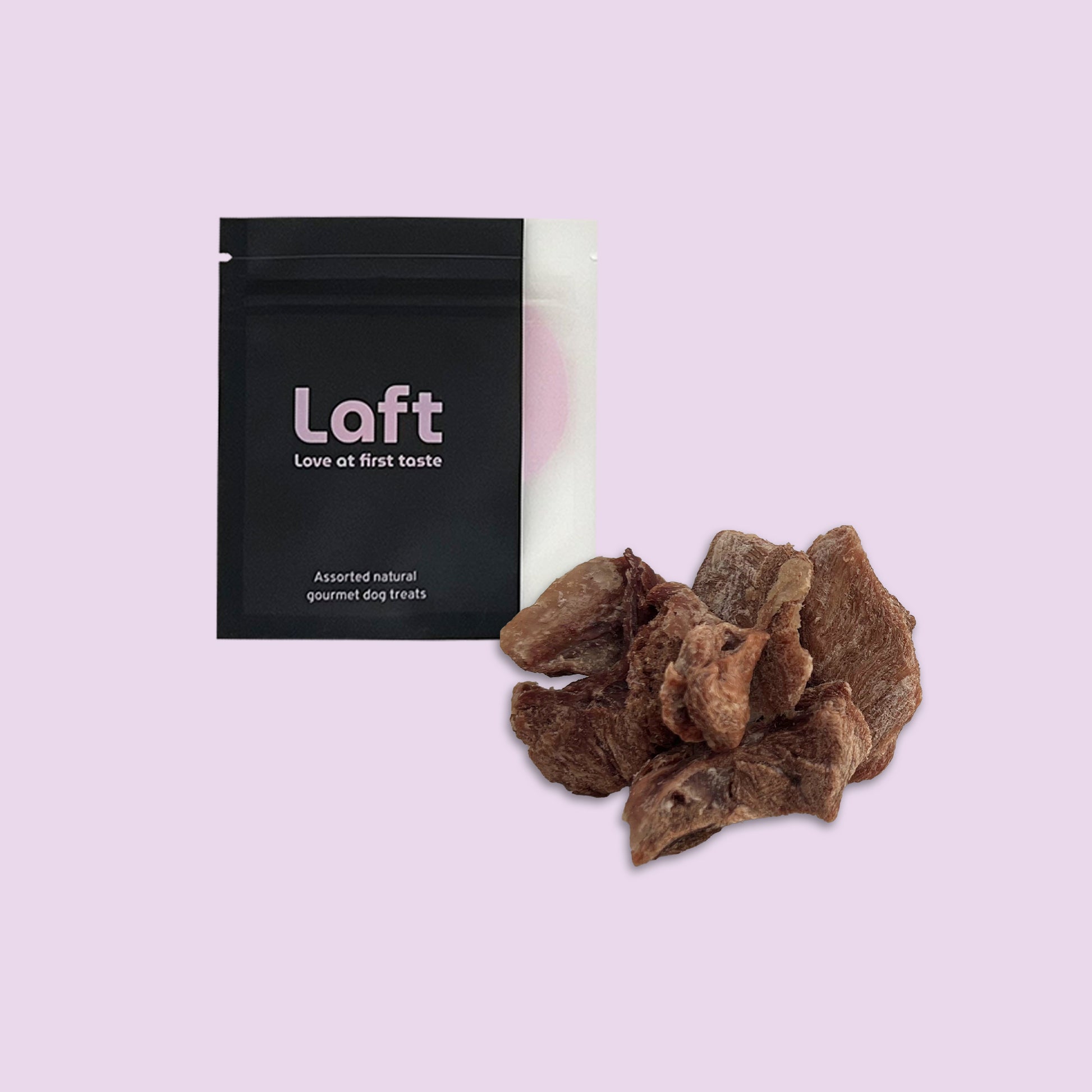 A black Laft Pet natural dog treat pouch placed next to a pile of freeze-dried turkey dog treats on a light purple background.