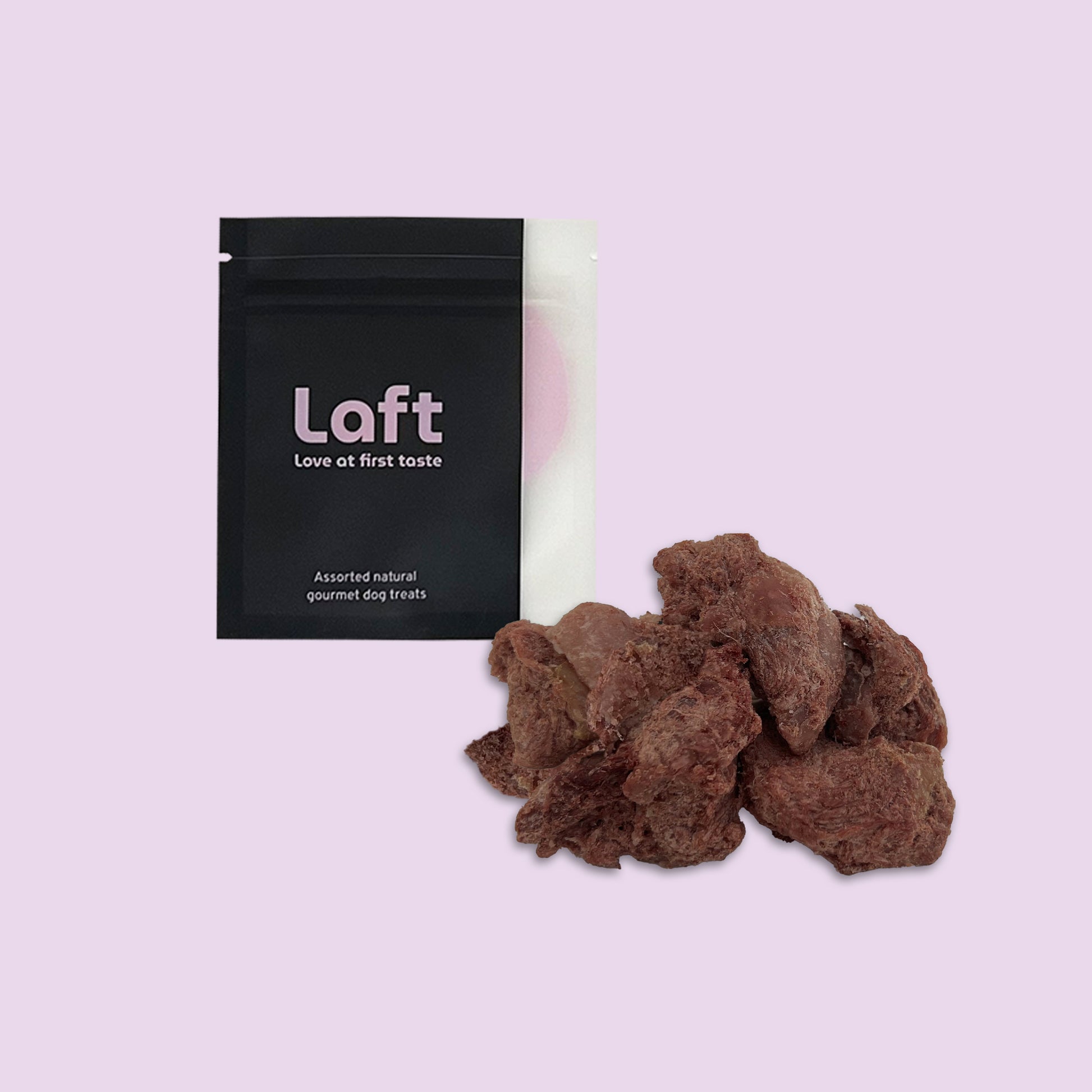 A black Laft Pet natural dog treat pouch placed next to a pile of freeze-dried wild boar dog treats on a light purple background.