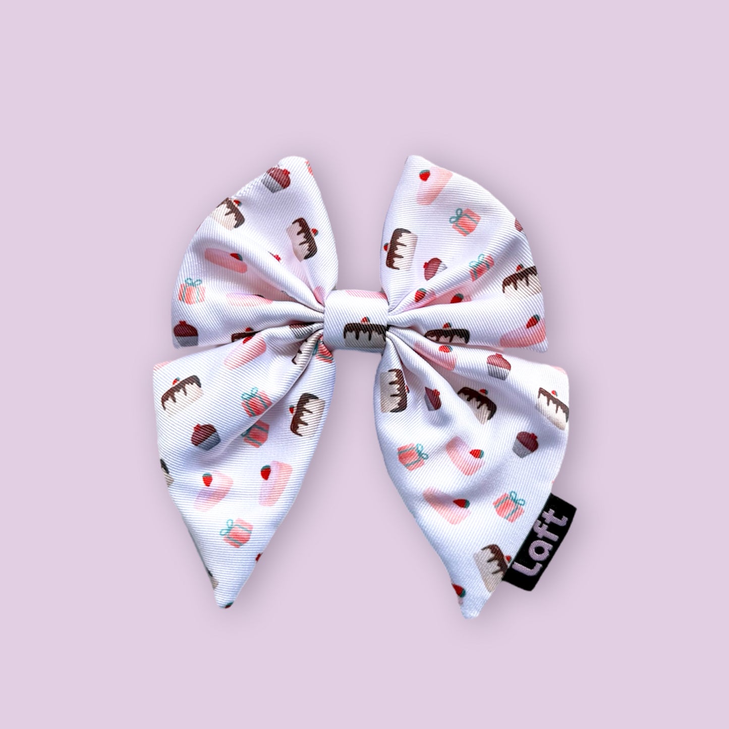 A white sailor bow with dessert print and a Laft label on the right displayed on a light purple background.