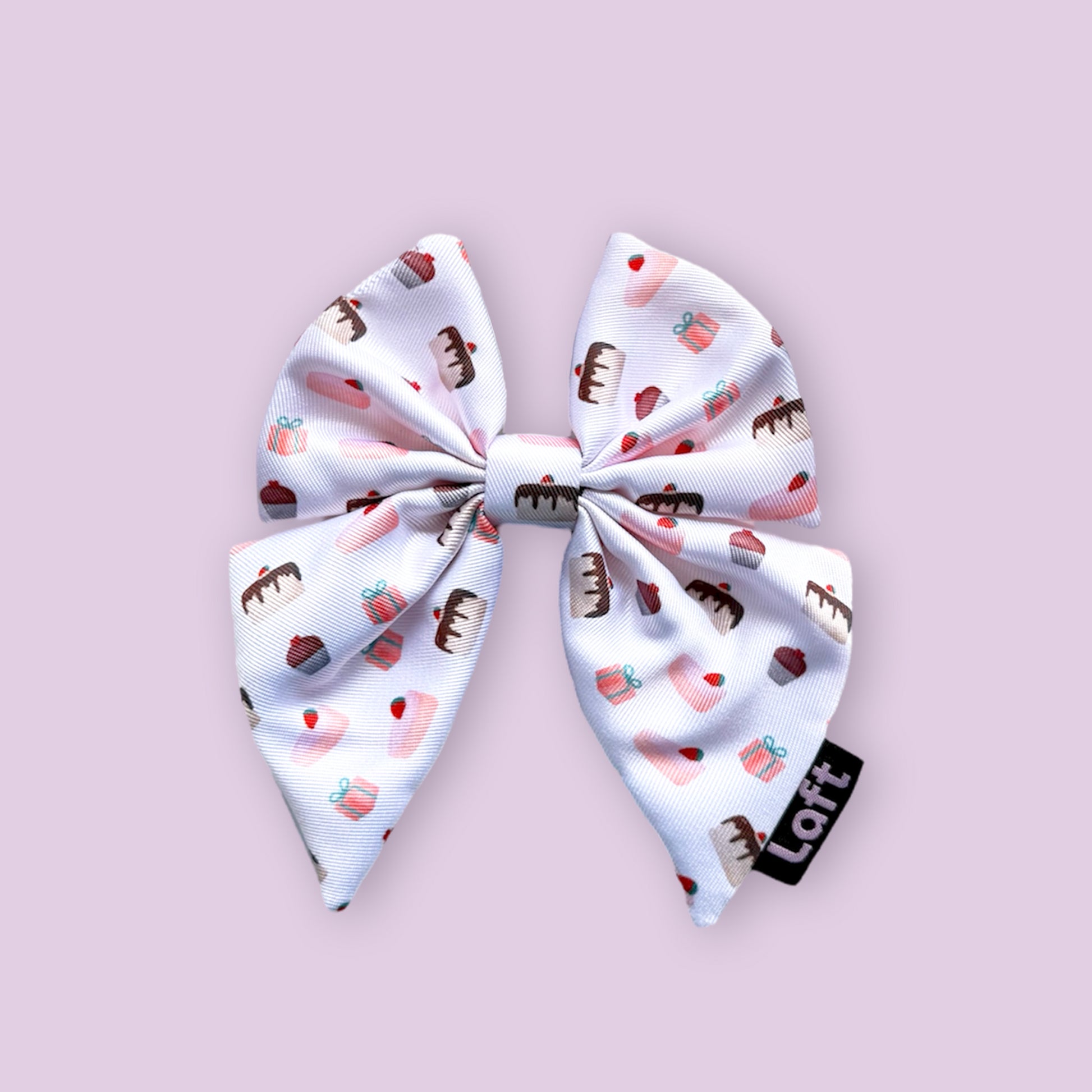 A white sailor bow with dessert print and a Laft label on the right displayed on a light purple background.